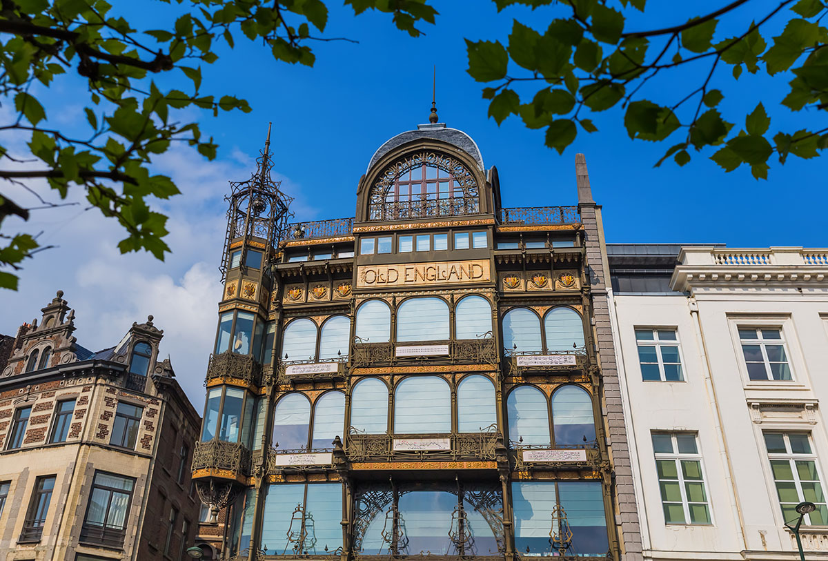 The musical instrument museum in Brussels with a yellow sign over a glass door set into a glass fronted building with ornate metal work all over its facade